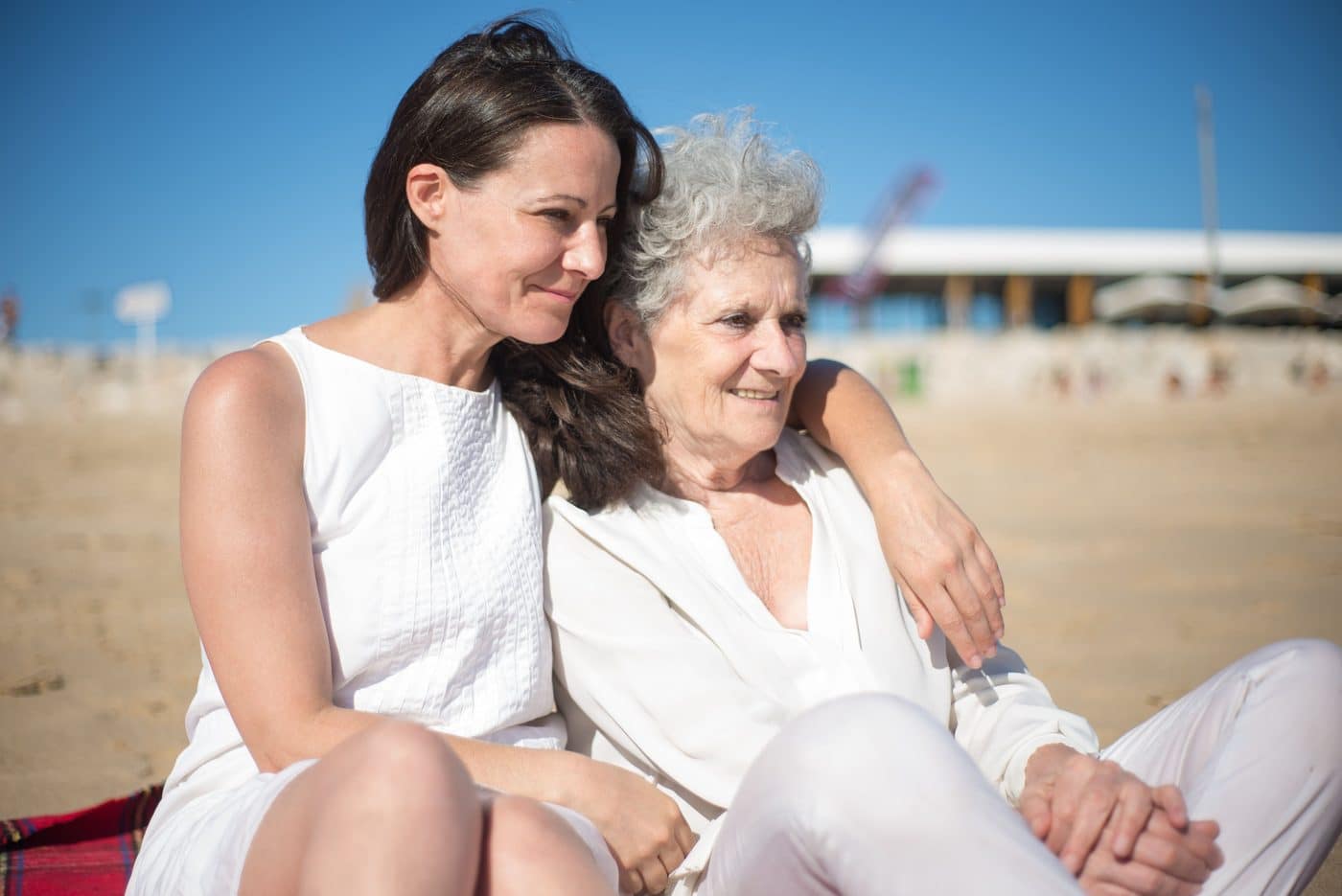 An adult daughter with her arm around her elderly mother.